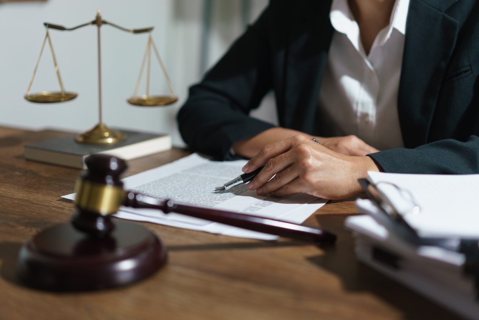 Person reviewing a document at a desk with balance scales and a gavel.