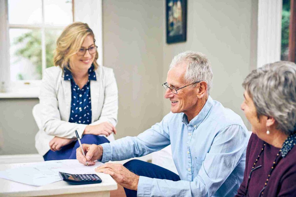 Older man signing paperwork at a table with two women.